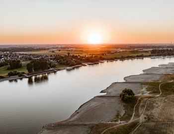 Sonnenuntergang mit Blick auf den Rhein, flache Strände und Dörfer im Hintergrund. Incentives im Schloss Friedestrom