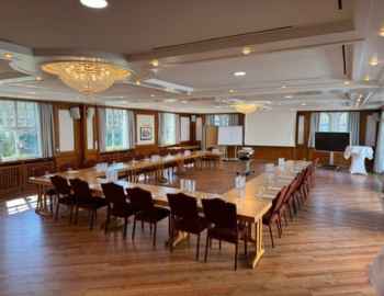 Ein Hufeisen Tischordnung für eine Tagung im Schloss Friedestrom. Beamer, Whiteboard und Fernseher stehen vorne.