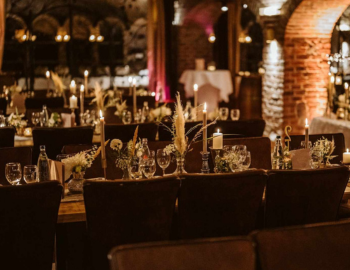 Weihnachtlich geschmückte lange Tische in einem Raum mit Backstein Säulen für eine Business Weihnachtsfeier.